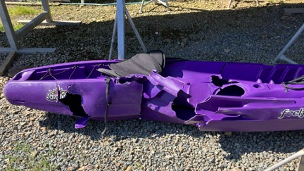 A crumpled purple kayak on the ground