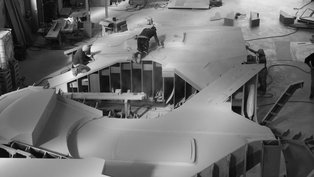 workers crawl over vessel being made at Manari Yachts