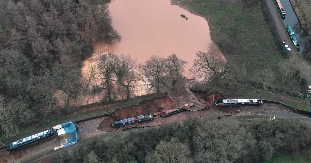 canal breach with two stricken houseboats in crater