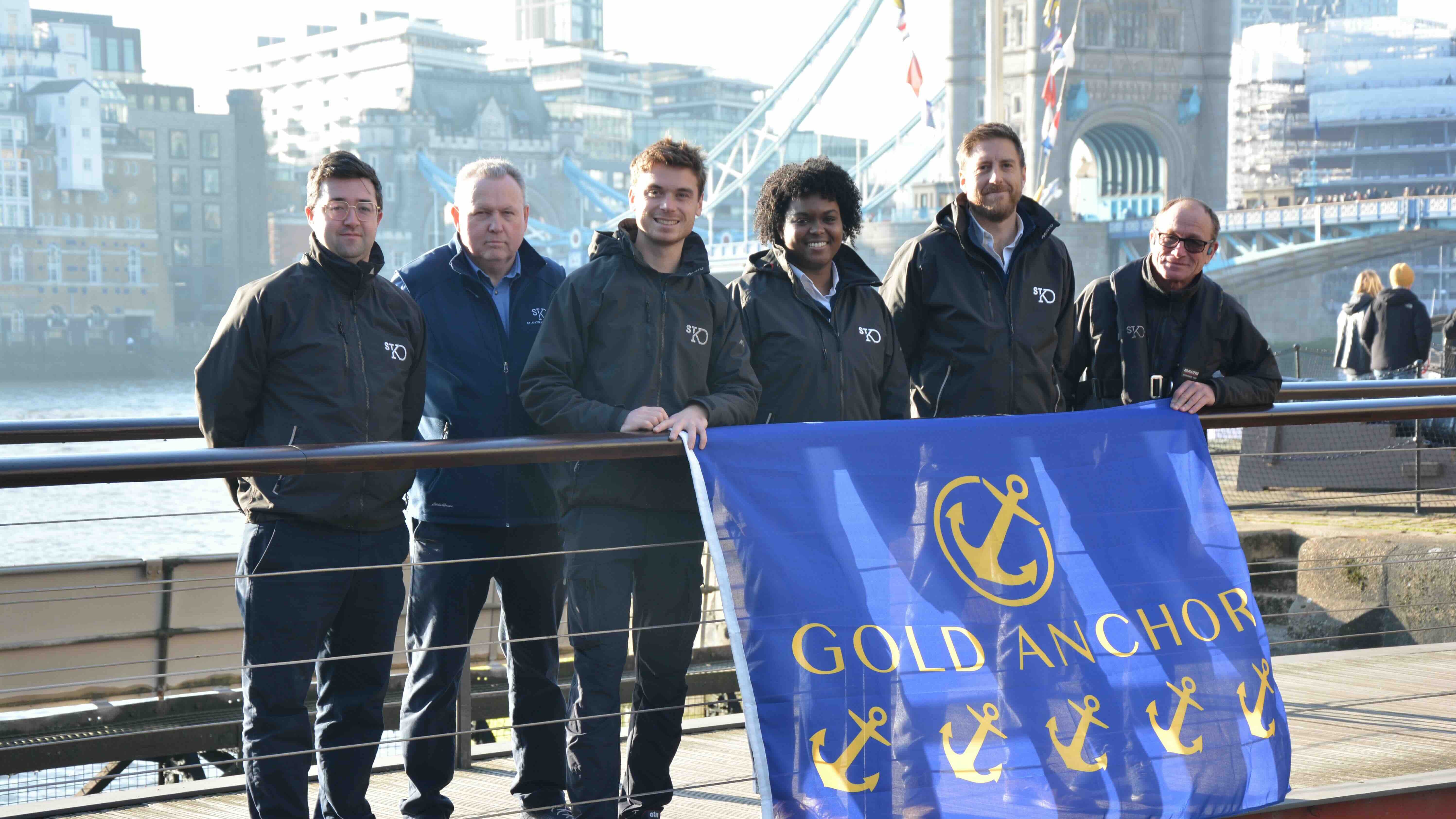 group of people in dark sailing jackets outside with blue banner