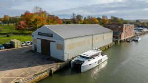 aluminium catamaran on dock beside a large commercial boat shed with