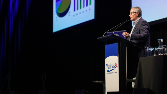 a man stands at a lectern and addresses a conference.