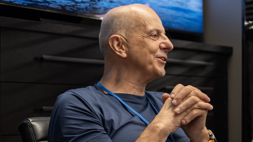 man in t shirt sits in front of screen with hands clasped together. This is Francis Lapp of Sunreef Yachts