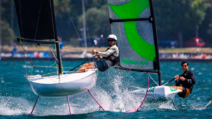 Two dinghy boats on foils with male sailors heading towards camper