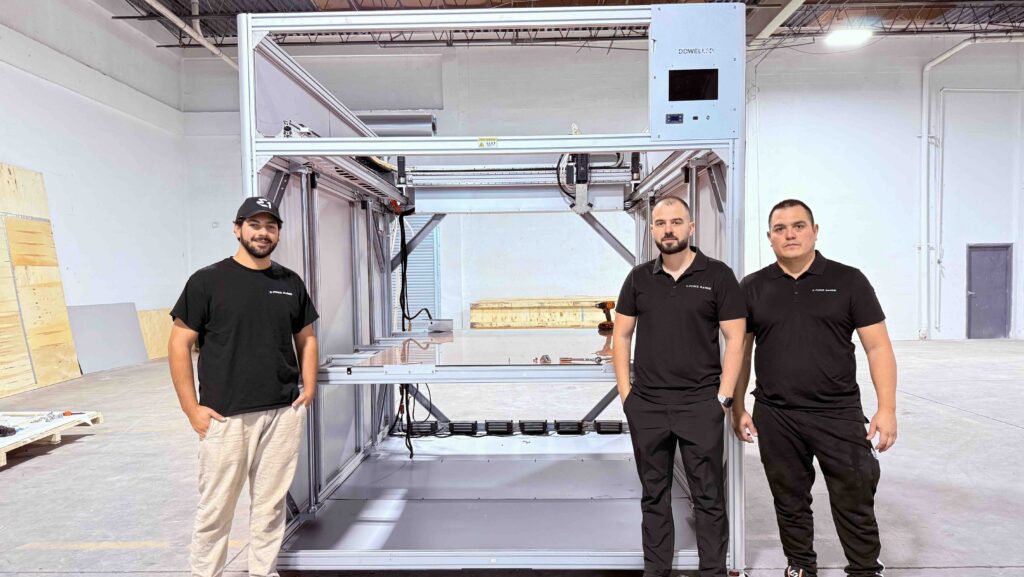 three men standing by 3D marine printing machine