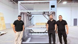 three men standing by 3D marine printing machine