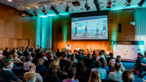 I delegati siedono in una sala e guardano le immagini del SailGP: questo è lo Yacht Racing Forum