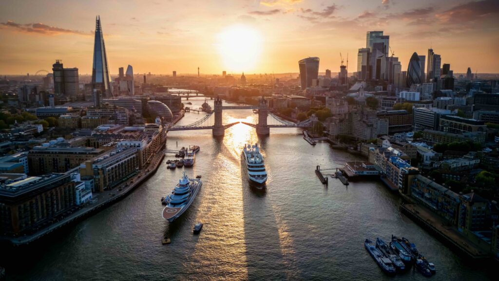 superyachts sailing up the Thames in London with city in background