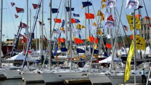 row of sailing boats moored at marina with flags