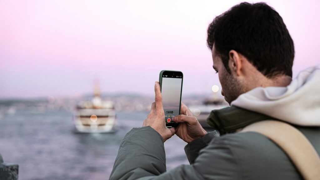A man taking a picture of a boat in the water