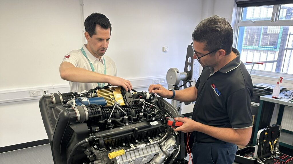 Two men work on a marine V8 engine in training room