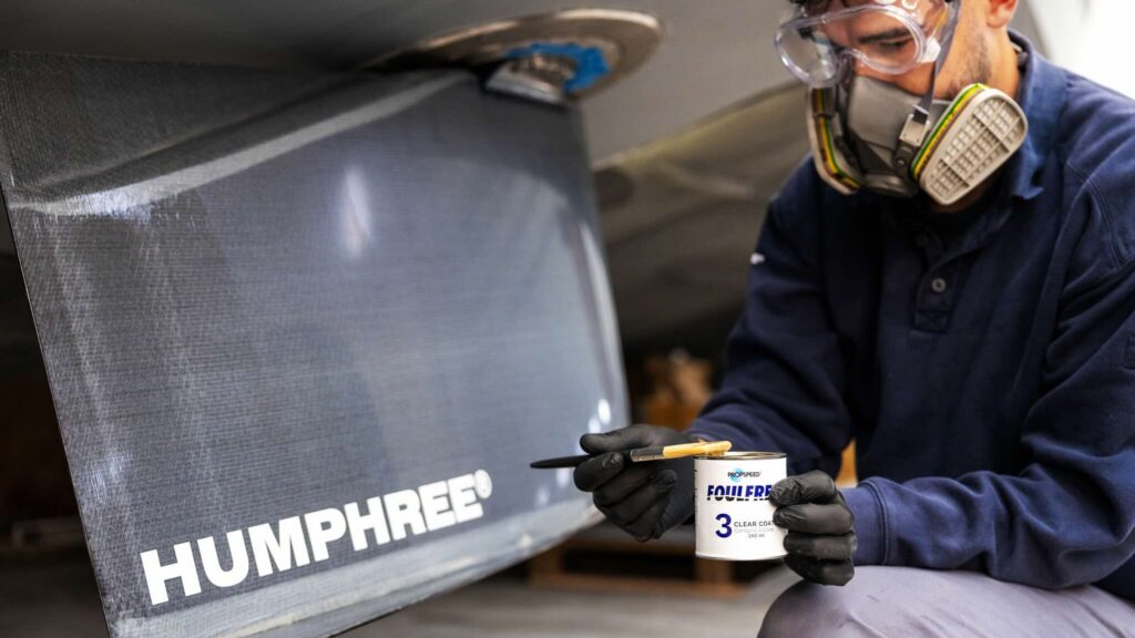 Workman holding can of antifoul paint next Humphree stabiliser fin