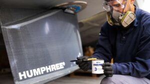 Workman holding can of antifoul paint next Humphree stabiliser fin