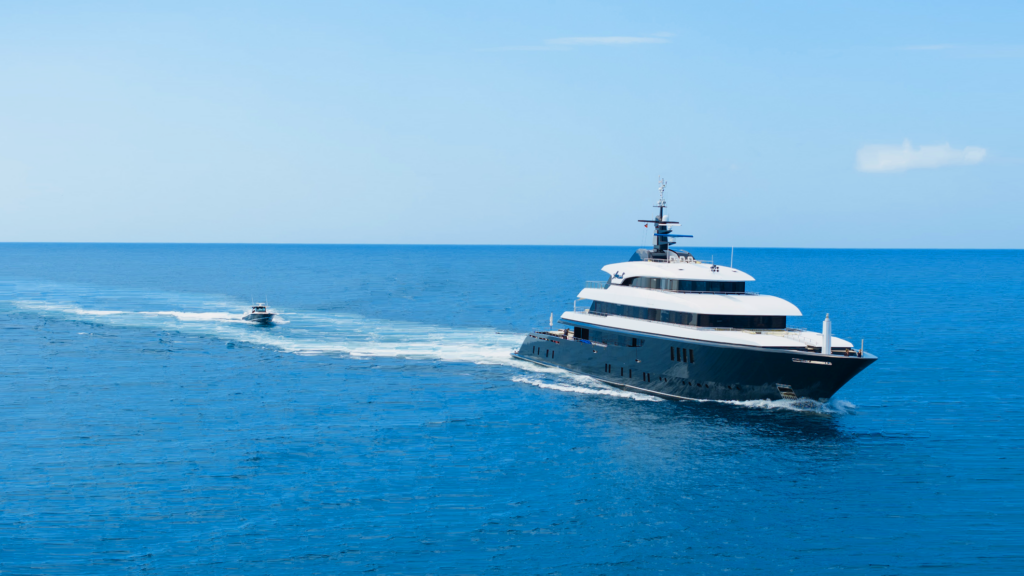 Superyacht with a tender behind it at sea