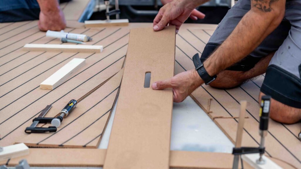 man's hands fitting cork decking on a boat