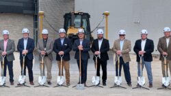 Line of men in suits with shovels in breaking ground ceremony