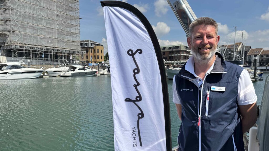 Chris Ibbotson stands next to a flag