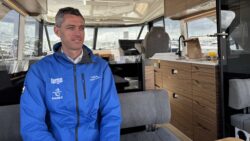 man in blue jacket sits onboard a boat - it's Guy Adams