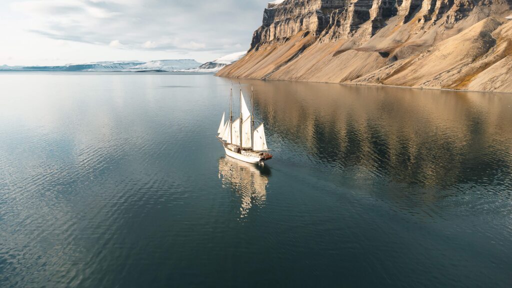 Boat in calm sea with cliffs in background