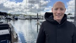 Oliver Lanza stands in black coat in a marina