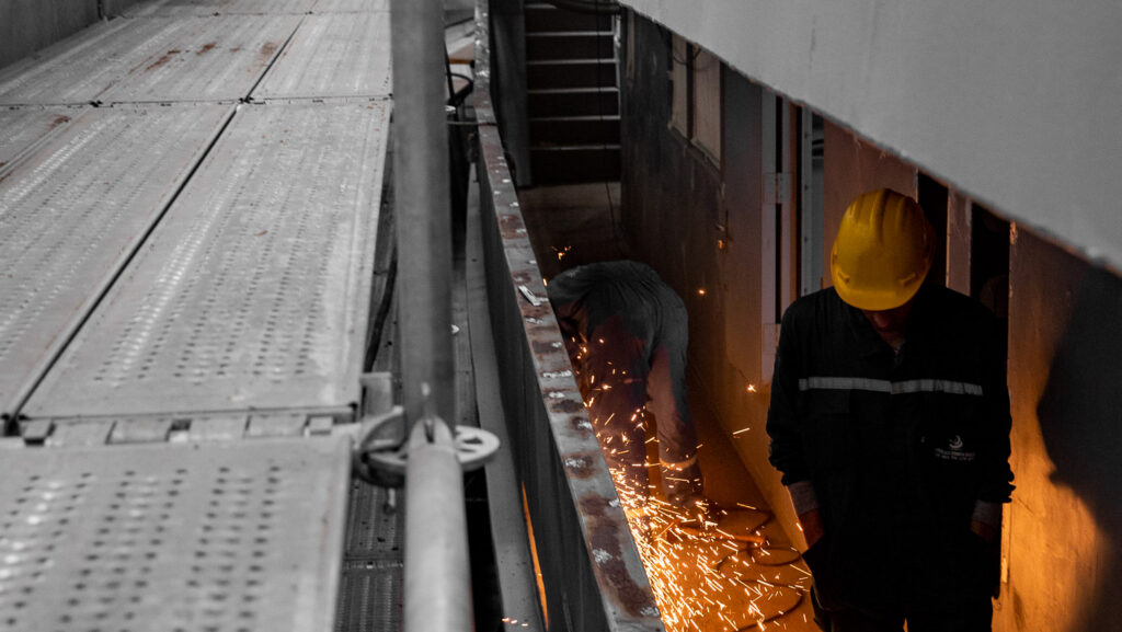 Person welding underneath superyacht in-build