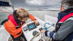 Two male sailors on a boat looking at navigation equipment
