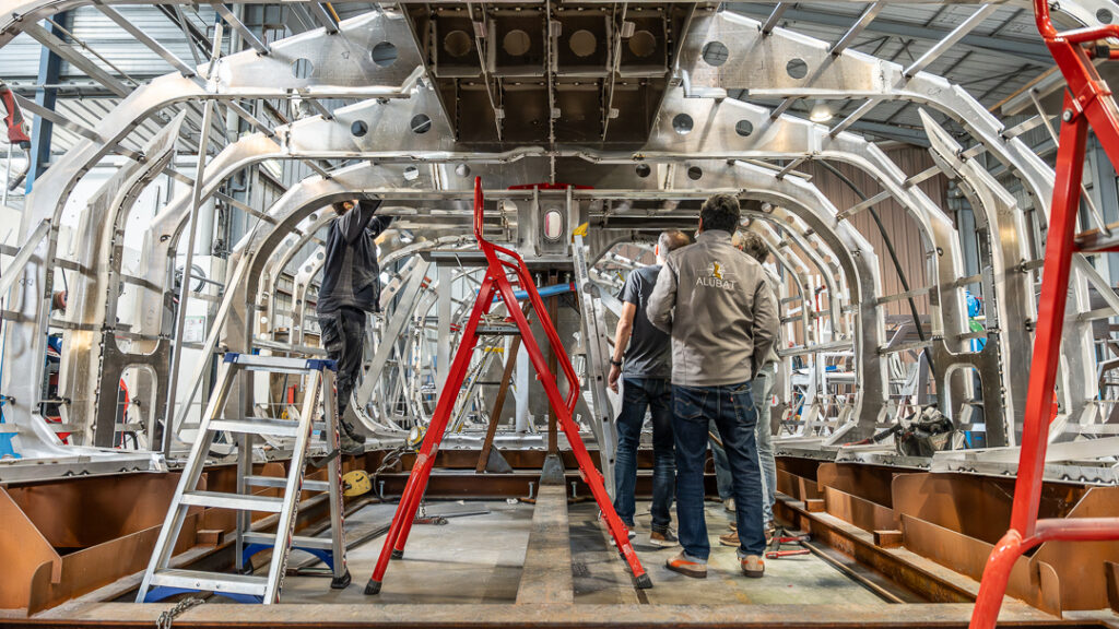 People stand underneath an aluminium ship's hull - which is being constructed