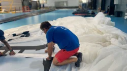 man in factory working on white sail fabric