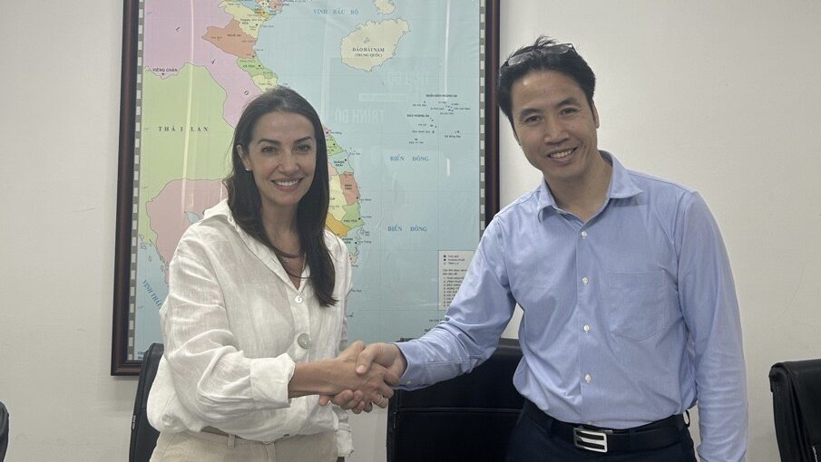 Two people in front of a world map shaking hands