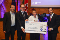 four business people holding big cheque at award ceremony