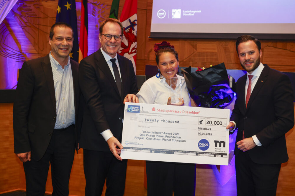 four business people holding big cheque at award ceremony
