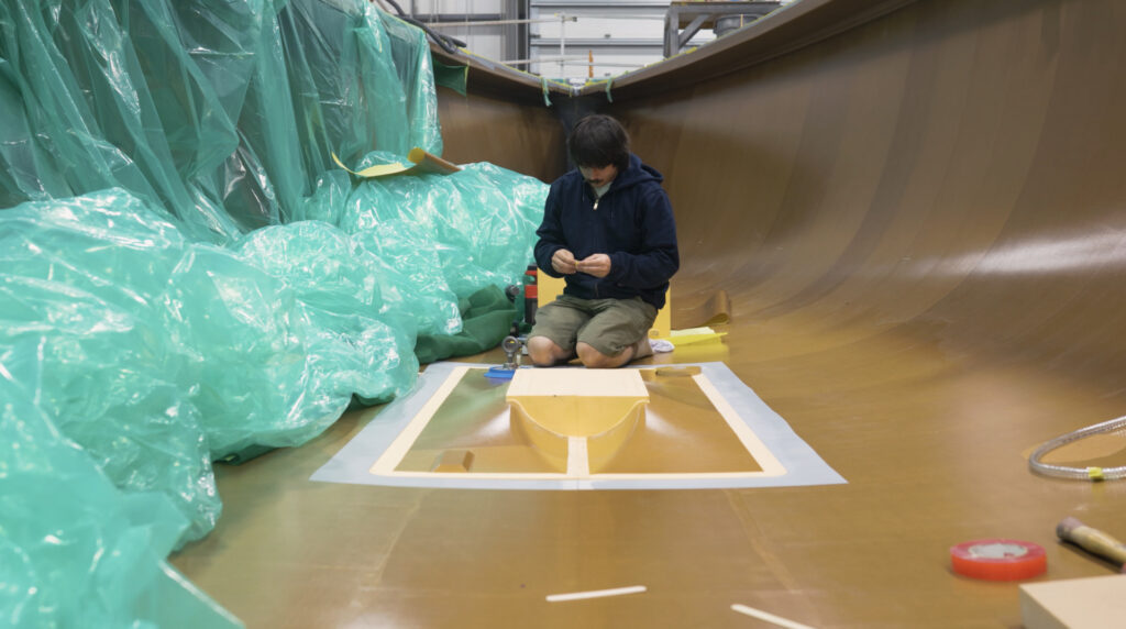 male worker sits in boat hull to illustrate Moores Brothers coming into 400F project