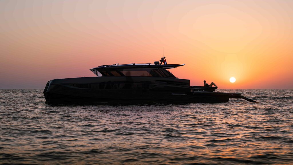 Side profile of the BRABUS ULTIMA 55 at anchor with the sun setting over the sea.