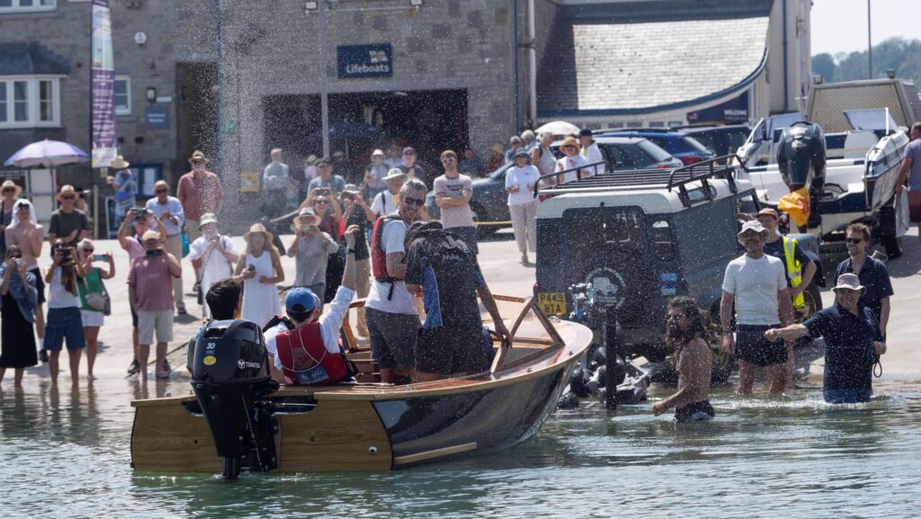 motor boat launched for first time with crowds cheering and waving