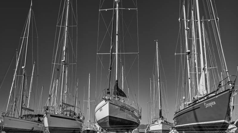 A black and white image of sailing yachts on the hard standing