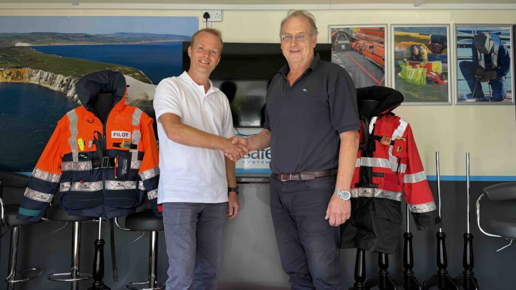 two men shaking hands in front of lifejacket display