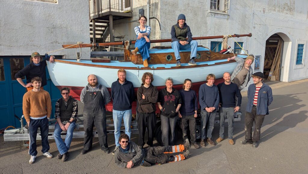 students from BBA arranged around a boat