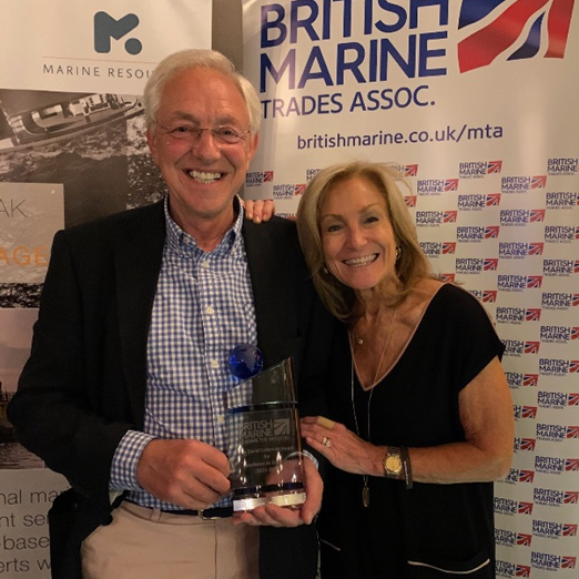 Two people standing together with an award between them