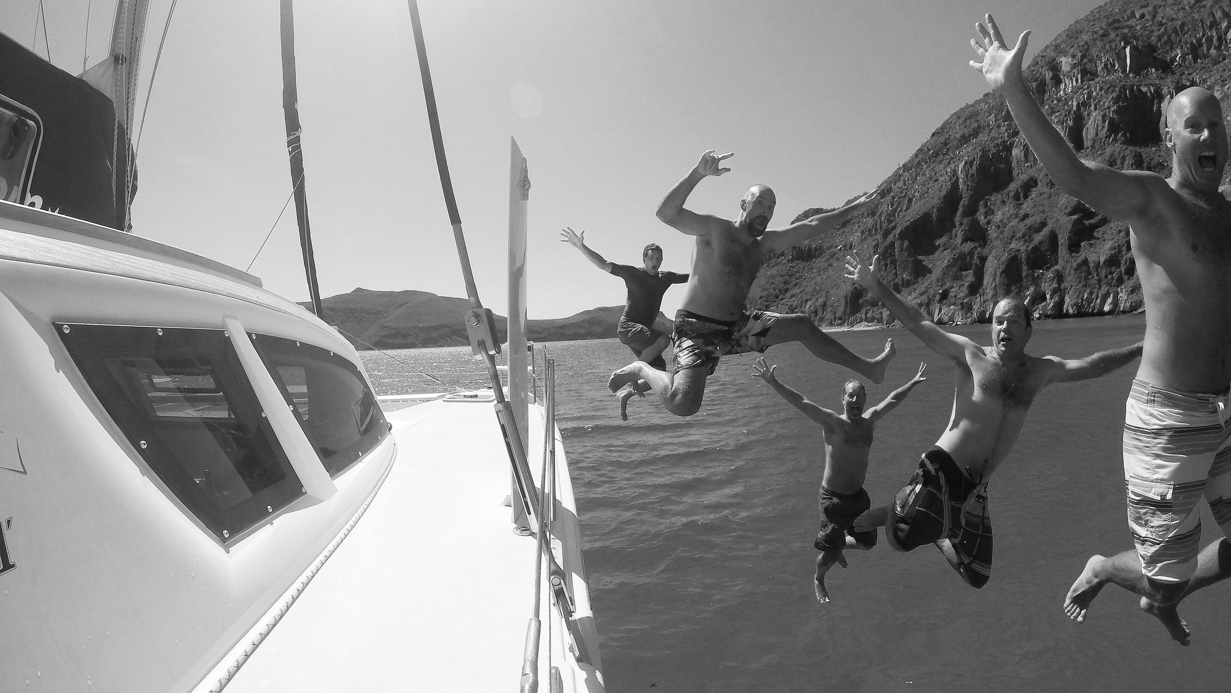 group of people jump off the side of a boat