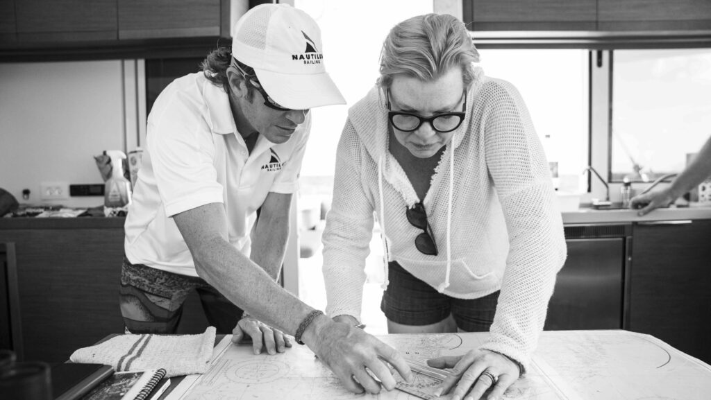 two people study charts on a boat