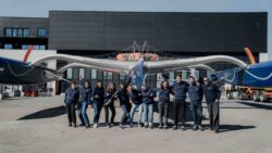 team of female sailors on land in front of foiling hull yacht