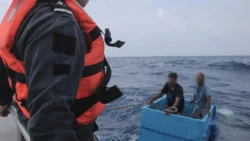 Two fishermen inside large blue cooler