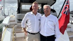 Dean Ling and Pete Hamyln Fairline stand on stern of boat with flag next to them