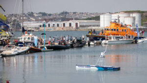 Marine AI’s autonomous surface vessel Guardian on the water at Plymouth Boat Fest 2026, with an RNLI lifeboat and other boats moored behind it.