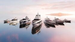 A fleet of Azimut motor yachts anchored on calm water at sunset.