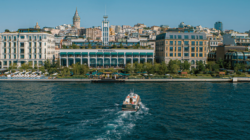 The Peninsula Istanbul hotel on the Bosphorus waterfront, with a boat passing in the foreground.