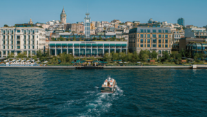 The Peninsula Istanbul hotel on the Bosphorus waterfront, with a boat passing in the foreground.
