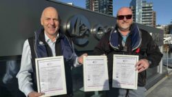 Two men with framed certificates
